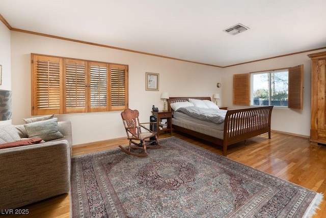 bedroom featuring baseboards, wood finished floors, visible vents, and crown molding