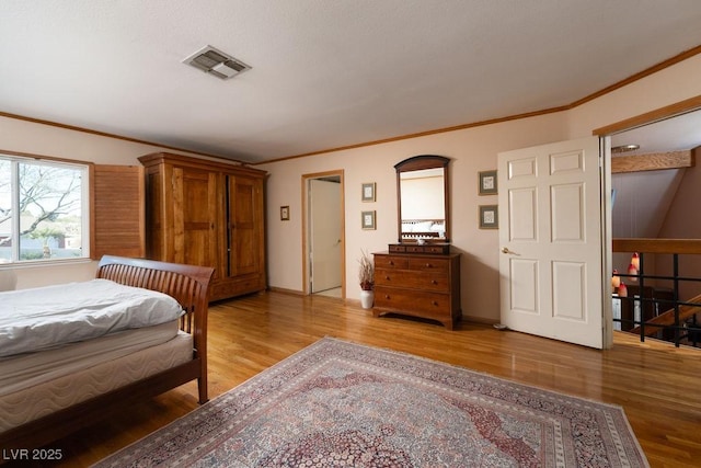 bedroom with light wood-style flooring, visible vents, baseboards, and ornamental molding