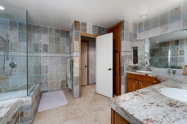 full bath featuring tile patterned flooring, a sink, tile walls, double vanity, and a stall shower