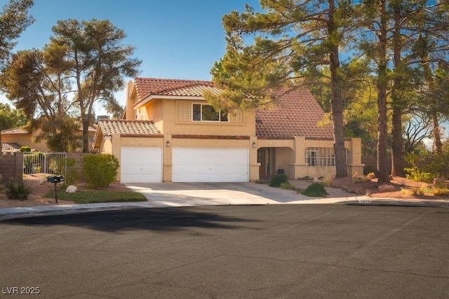 mediterranean / spanish home with a garage, fence, a tile roof, driveway, and stucco siding