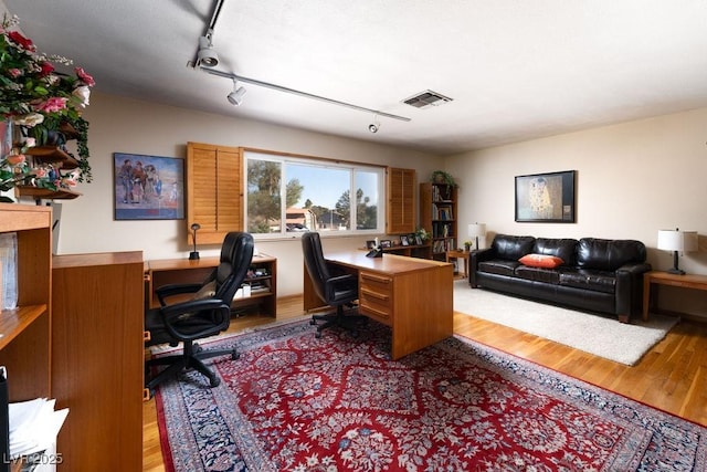 office area with wood finished floors, visible vents, and rail lighting