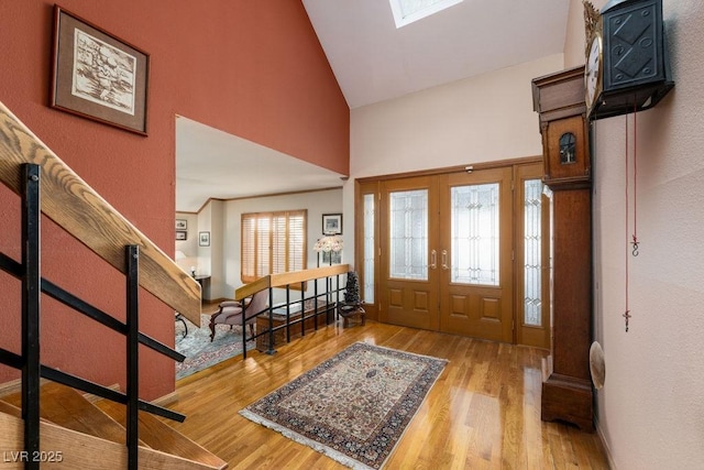 entrance foyer featuring a skylight, high vaulted ceiling, and wood finished floors