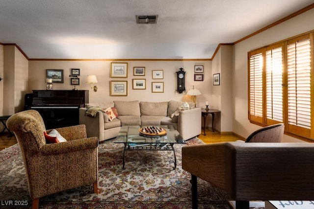 living room with visible vents, crown molding, baseboards, and wood finished floors