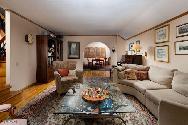 living room featuring arched walkways, crown molding, stairs, and light wood-style floors