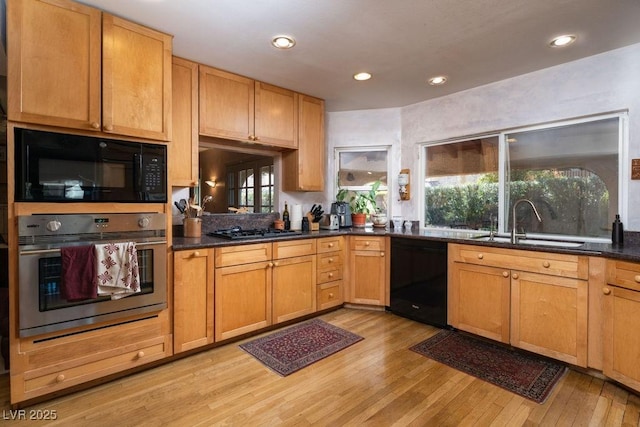 kitchen featuring black appliances, light wood finished floors, a sink, and recessed lighting