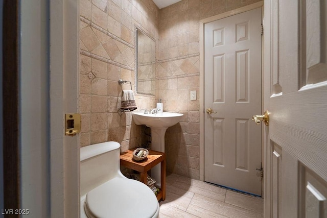 half bathroom with toilet and tile walls