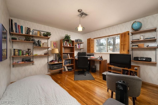 office space with wood finished floors, visible vents, and wallpapered walls