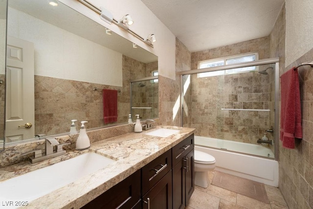 bathroom featuring toilet, double vanity, enclosed tub / shower combo, and a sink