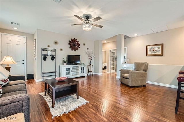 living room featuring a ceiling fan, baseboards, visible vents, and wood finished floors