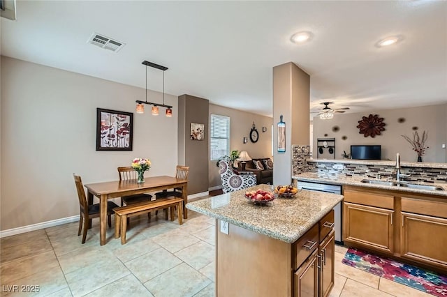 kitchen featuring a kitchen island, a sink, visible vents, stainless steel dishwasher, and backsplash