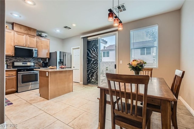 kitchen featuring tasteful backsplash, appliances with stainless steel finishes, visible vents, and a center island