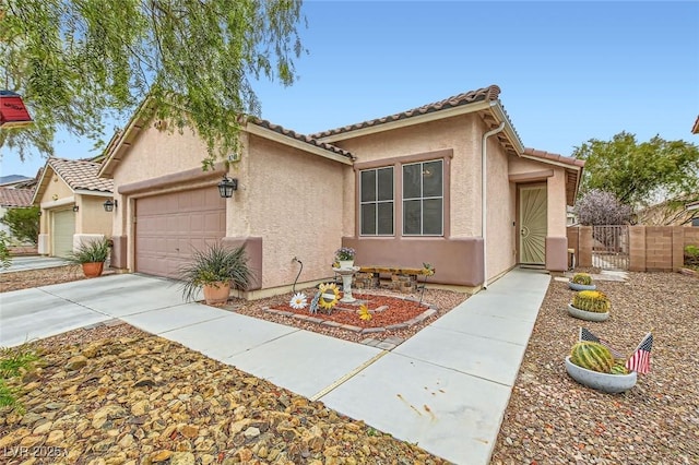 view of front of home with a tile roof, stucco siding, concrete driveway, a gate, and a garage