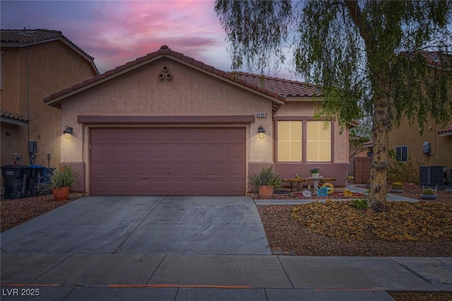 view of front of home with a garage, driveway, a tiled roof, central air condition unit, and stucco siding