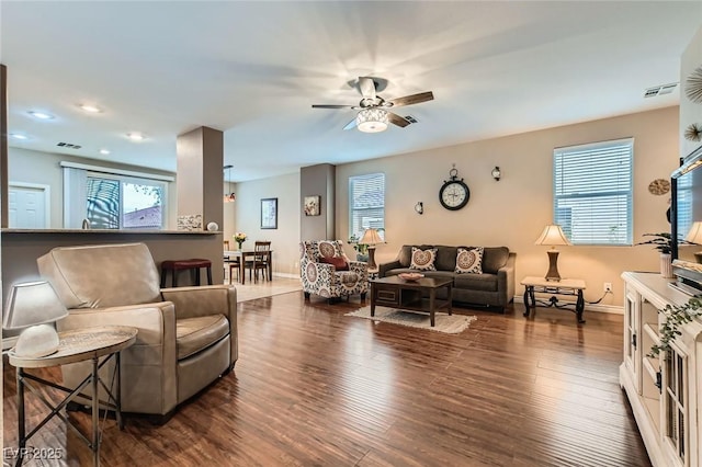 living room with a wealth of natural light, visible vents, baseboards, and wood finished floors