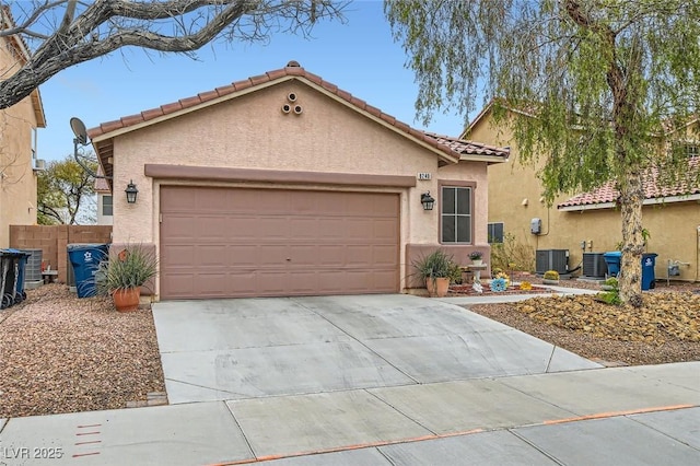 mediterranean / spanish house featuring central air condition unit, stucco siding, concrete driveway, fence, and a garage