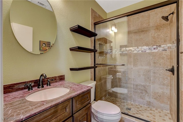 bathroom with toilet, a stall shower, visible vents, and vanity