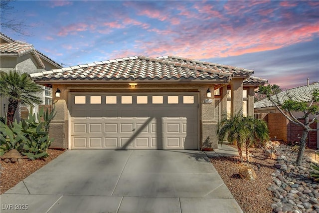 view of front of home with concrete driveway, an attached garage, a tiled roof, and stucco siding