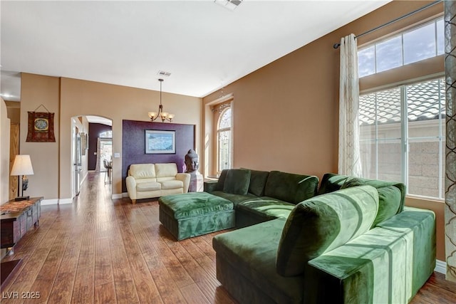 living area featuring plenty of natural light, arched walkways, and hardwood / wood-style floors