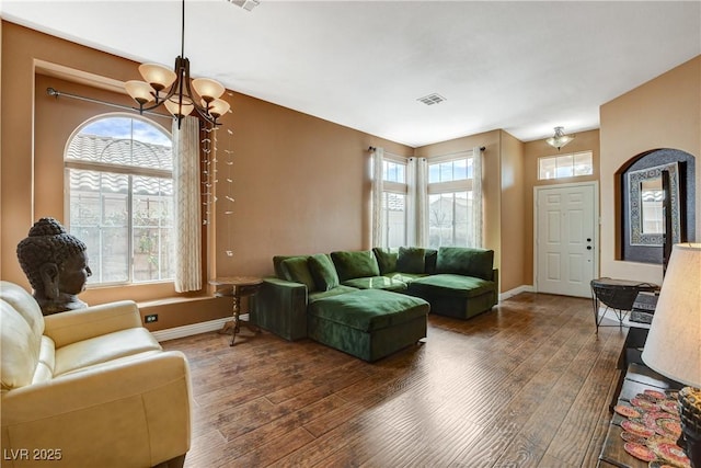 living room featuring an inviting chandelier, baseboards, visible vents, and wood finished floors