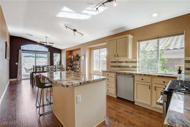 kitchen with stainless steel appliances, vaulted ceiling, plenty of natural light, and cream cabinets