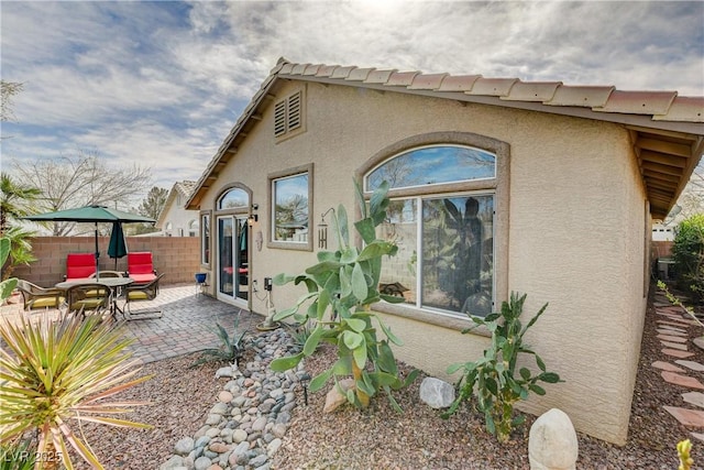 back of house with fence, a patio, and stucco siding