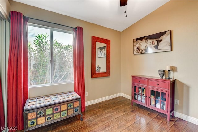 interior space with ceiling fan, baseboards, vaulted ceiling, and wood finished floors