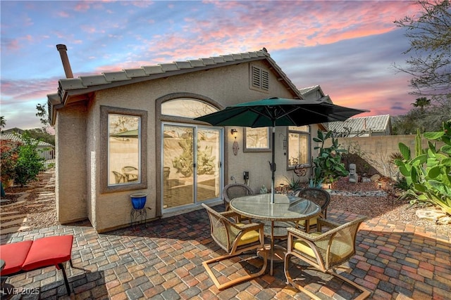 patio terrace at dusk featuring outdoor dining space and fence