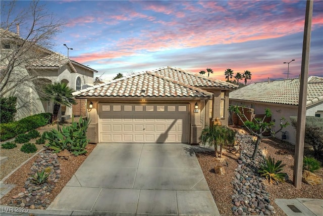 mediterranean / spanish house with a tile roof, driveway, an attached garage, and stucco siding