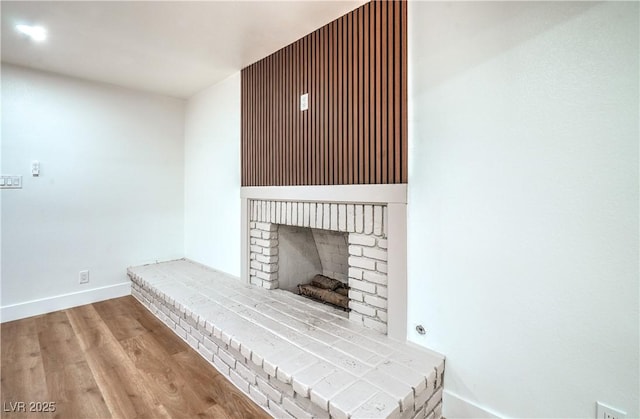 room details with a fireplace, wood finished floors, and baseboards