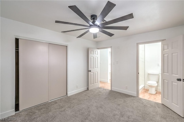 unfurnished bedroom featuring baseboards, a ceiling fan, ensuite bathroom, carpet flooring, and a closet