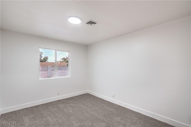 unfurnished room with dark carpet, visible vents, and baseboards