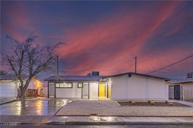 view of front of property featuring fence, concrete driveway, and stucco siding