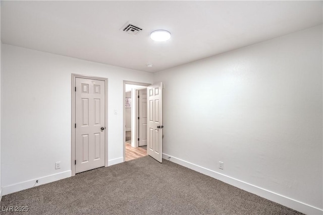 spare room featuring carpet, visible vents, and baseboards