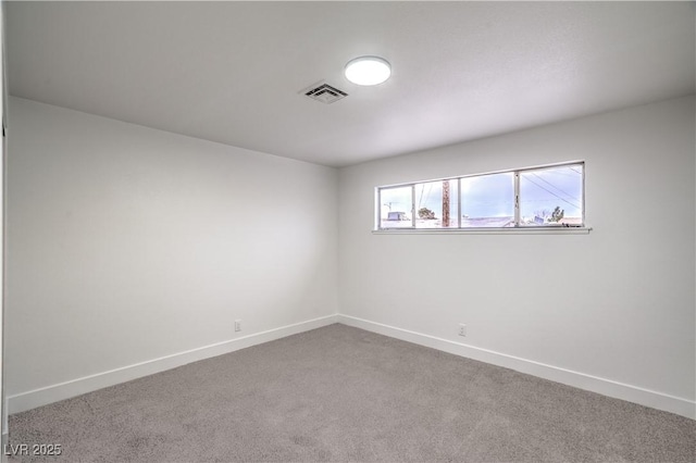 empty room with carpet, visible vents, and baseboards