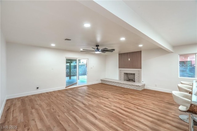 unfurnished living room with light wood finished floors, a brick fireplace, baseboards, and recessed lighting