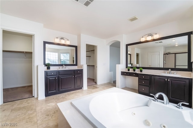 bathroom with a whirlpool tub, a sink, and visible vents