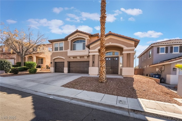 mediterranean / spanish-style home with a garage, driveway, a tiled roof, and stucco siding