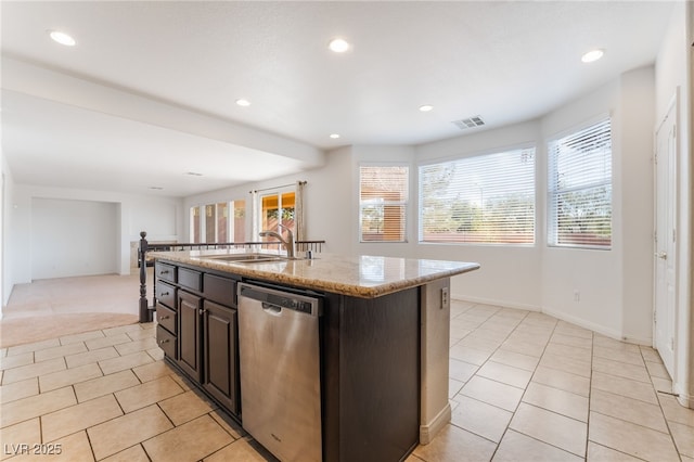 kitchen with light tile patterned floors, visible vents, dishwasher, an island with sink, and light stone counters