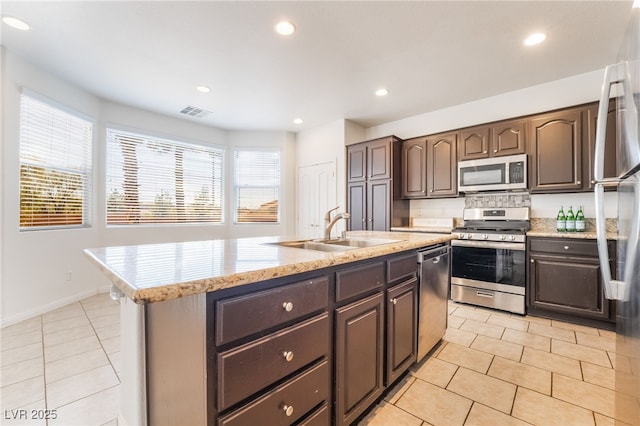 kitchen with light tile patterned floors, stainless steel appliances, visible vents, a sink, and dark brown cabinetry