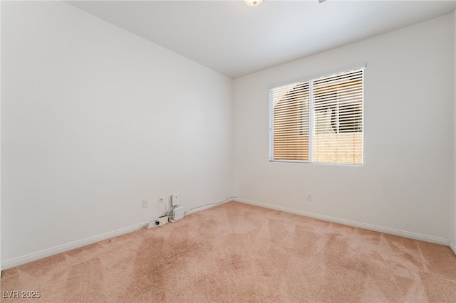 spare room featuring light colored carpet and baseboards