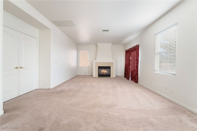 unfurnished living room with a fireplace, carpet flooring, visible vents, and baseboards