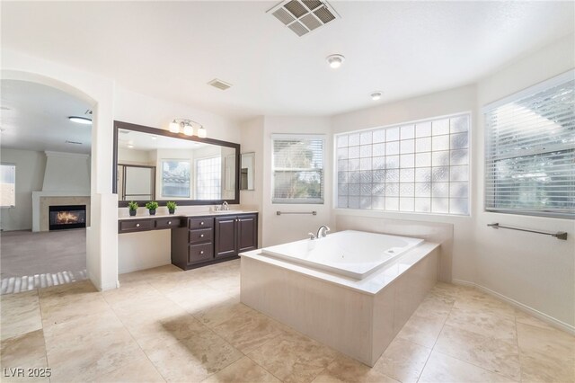 bathroom with a large fireplace, visible vents, vanity, and a bath