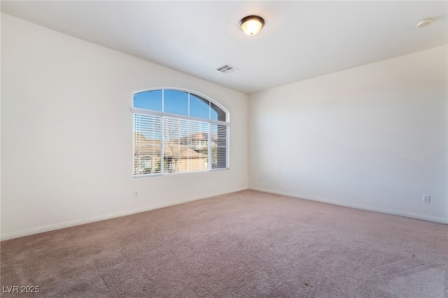 empty room with carpet, visible vents, and baseboards