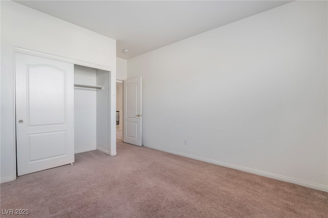 unfurnished bedroom featuring baseboards, a closet, and light colored carpet