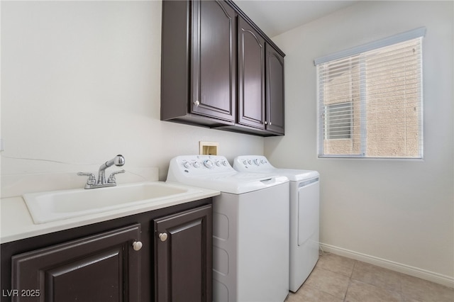 laundry room featuring cabinet space, light tile patterned floors, baseboards, washing machine and dryer, and a sink