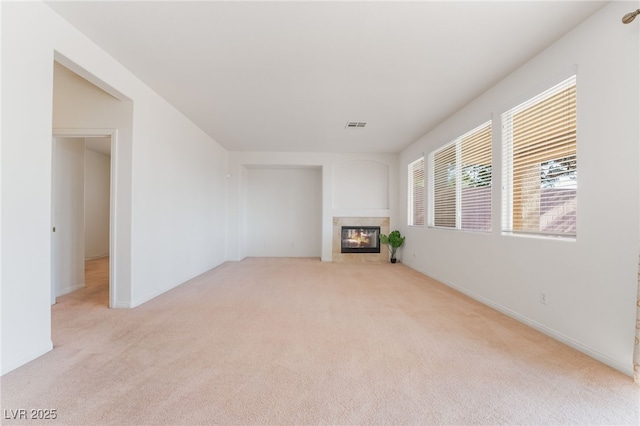 unfurnished living room featuring light carpet, a glass covered fireplace, and visible vents