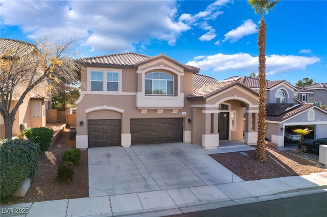 mediterranean / spanish-style home featuring a garage, concrete driveway, a tiled roof, and stucco siding