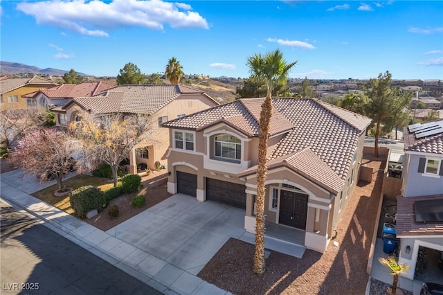 mediterranean / spanish-style home featuring a tile roof, driveway, an attached garage, and stucco siding