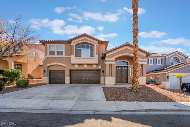 mediterranean / spanish-style house with concrete driveway, an attached garage, a tile roof, and stucco siding