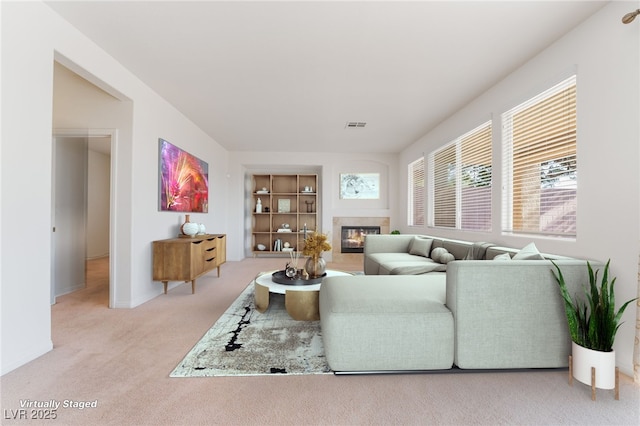 carpeted living area featuring visible vents, a fireplace, and baseboards